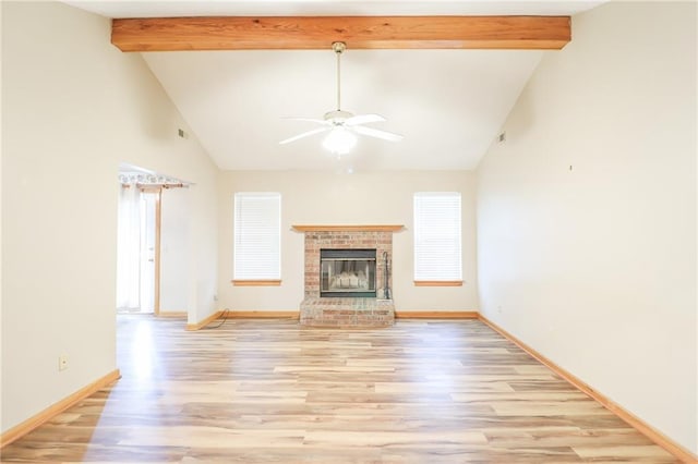 unfurnished living room with beamed ceiling, light wood finished floors, a brick fireplace, baseboards, and a ceiling fan