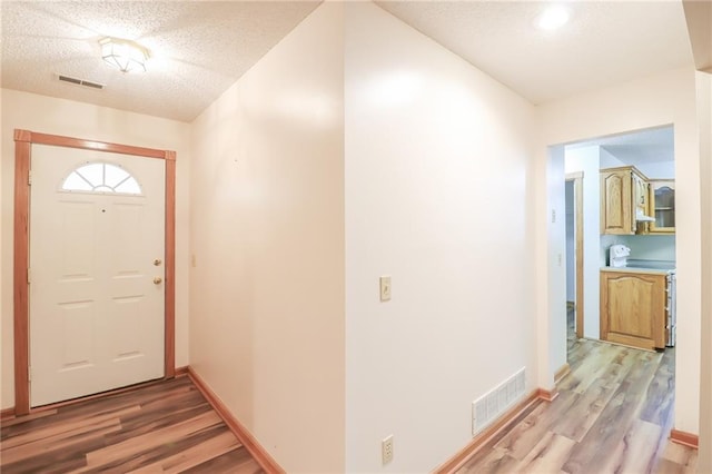 interior space with visible vents, a textured ceiling, and light wood finished floors