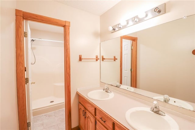 full bath with double vanity, walk in shower, and a sink