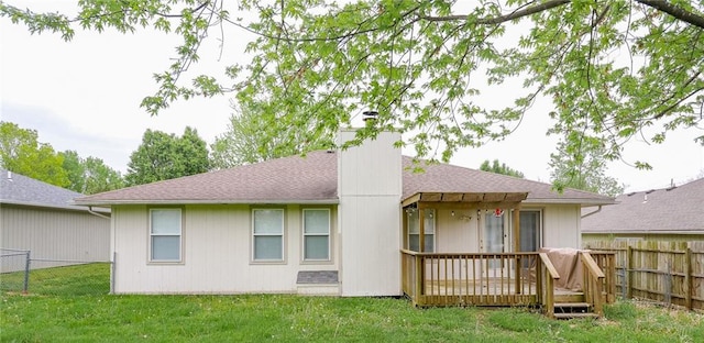 back of property with a lawn, a chimney, a wooden deck, and a fenced backyard
