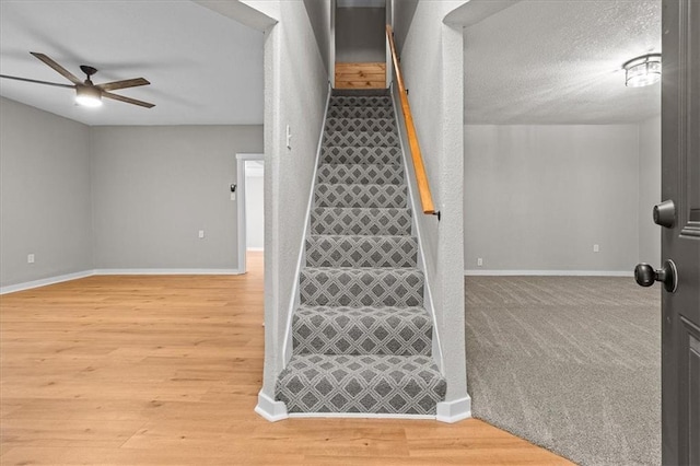 stairway featuring baseboards, a ceiling fan, and wood finished floors