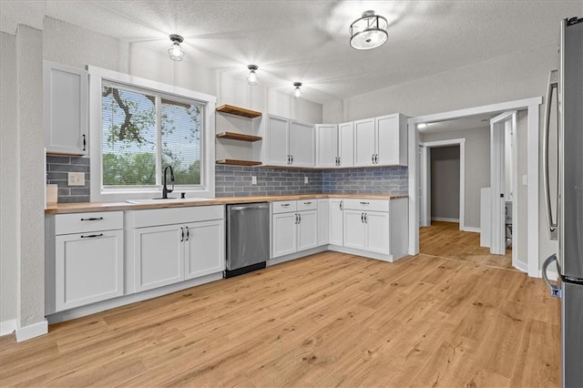 kitchen with a sink, wood counters, tasteful backsplash, and stainless steel appliances