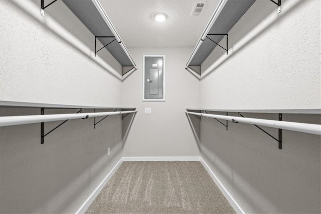 walk in closet with carpet floors, visible vents, and electric panel