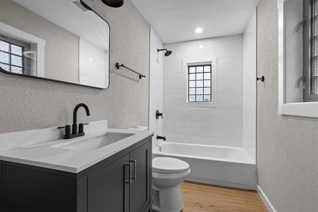 bathroom featuring a textured ceiling, wood finished floors, vanity, toilet, and a textured wall