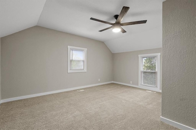 bonus room featuring a ceiling fan, a textured wall, vaulted ceiling, and carpet