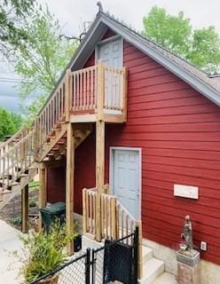 rear view of house with fence and stairs