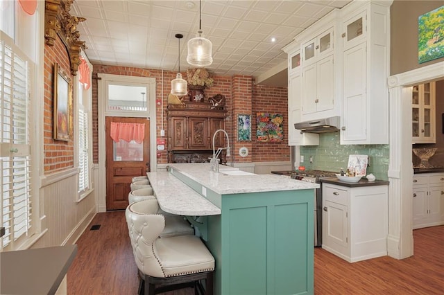 kitchen featuring white cabinets, stainless steel range, a sink, and light wood-style flooring