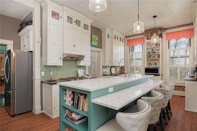 kitchen featuring open shelves, stainless steel appliances, white cabinetry, wood finished floors, and under cabinet range hood