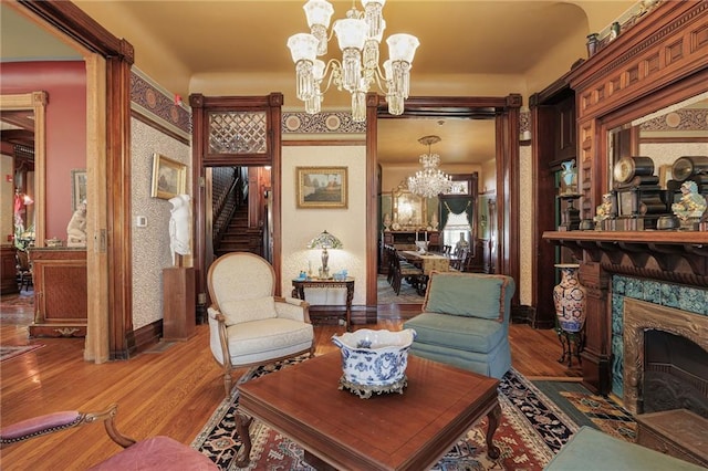 living area with a fireplace, stairs, light wood-style flooring, and a chandelier