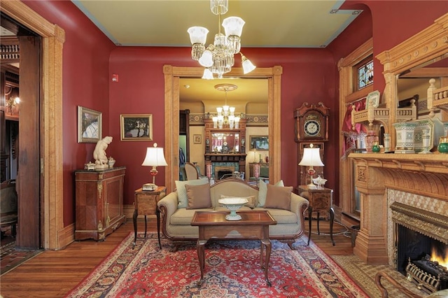 living area with baseboards, a notable chandelier, wood finished floors, and a fireplace