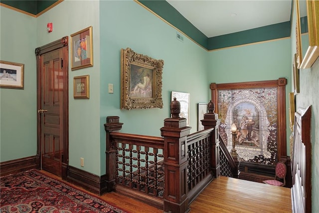 staircase with baseboards, visible vents, and wood finished floors