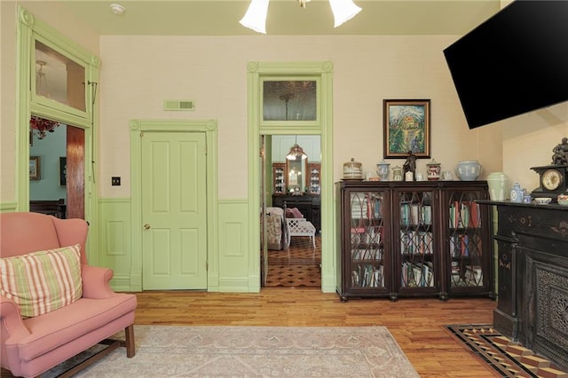 living area featuring visible vents, wood finished floors, and a wainscoted wall