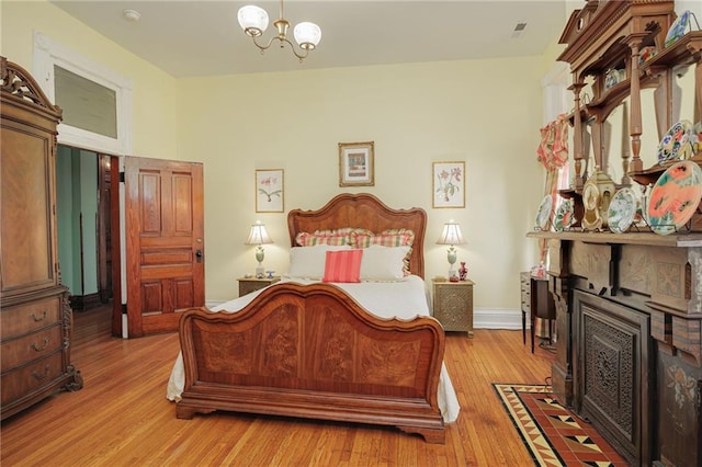 bedroom featuring baseboards, a chandelier, and light wood-type flooring