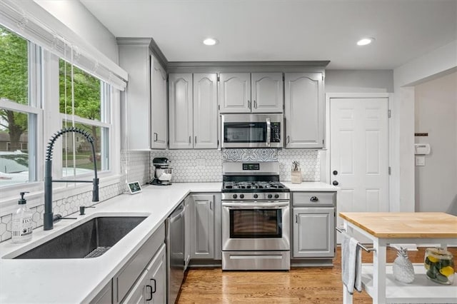 kitchen featuring light countertops, a sink, appliances with stainless steel finishes, and gray cabinets