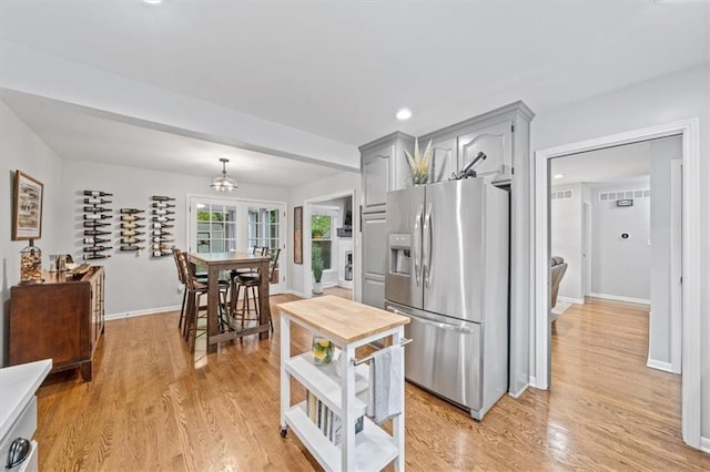 kitchen featuring baseboards, gray cabinets, light wood finished floors, and stainless steel refrigerator with ice dispenser
