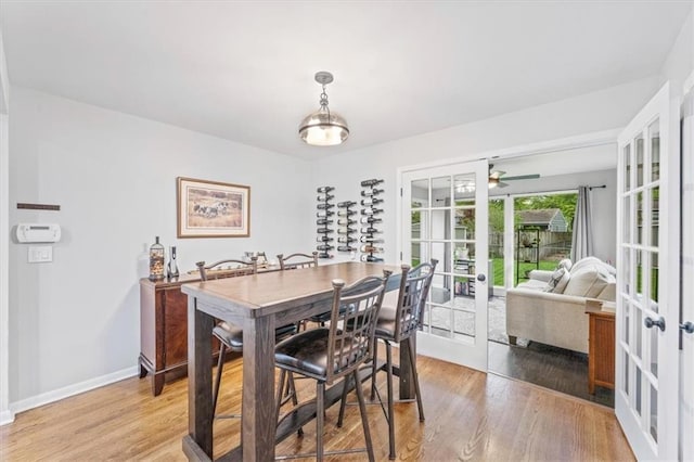 dining space featuring baseboards, a ceiling fan, french doors, and light wood finished floors