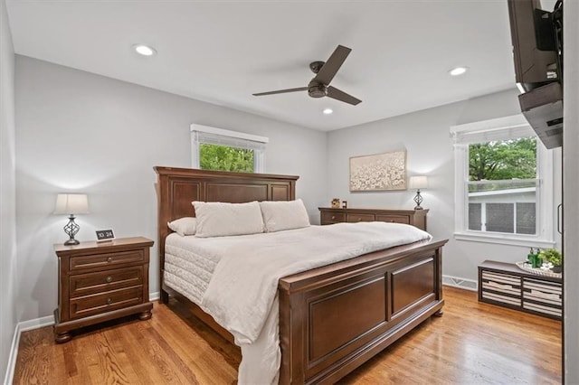 bedroom featuring baseboards, light wood finished floors, and multiple windows