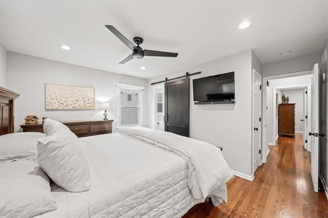 bedroom with wood finished floors, baseboards, ceiling fan, recessed lighting, and a barn door