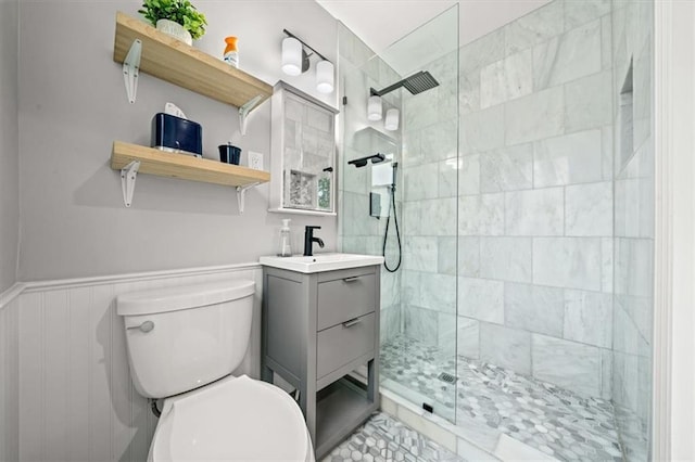 full bath featuring toilet, walk in shower, a wainscoted wall, and vanity
