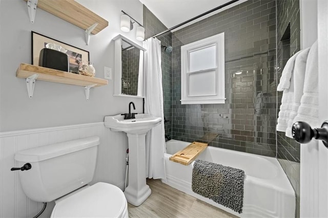 full bathroom featuring shower / bath combo with shower curtain, a wainscoted wall, toilet, and wood finished floors