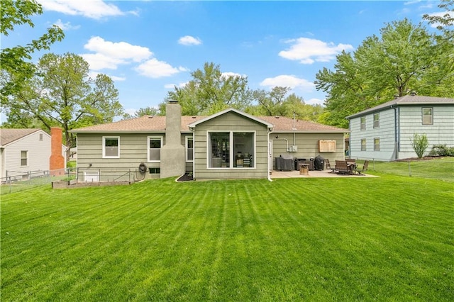 rear view of property featuring a lawn, fence, a chimney, and a patio area