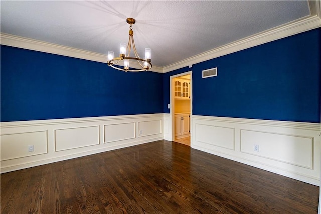 unfurnished room featuring crown molding, a wainscoted wall, visible vents, and a chandelier