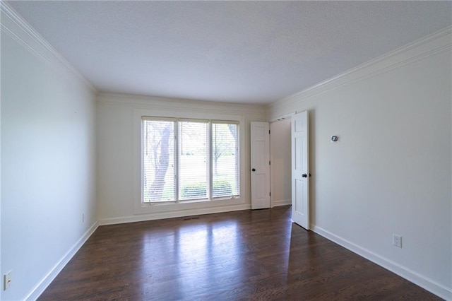 spare room featuring baseboards, ornamental molding, and dark wood-type flooring