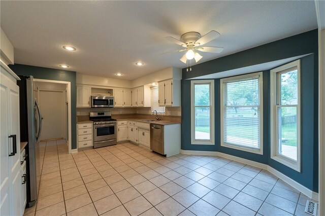 kitchen featuring a sink, ceiling fan, white cabinetry, baseboards, and appliances with stainless steel finishes