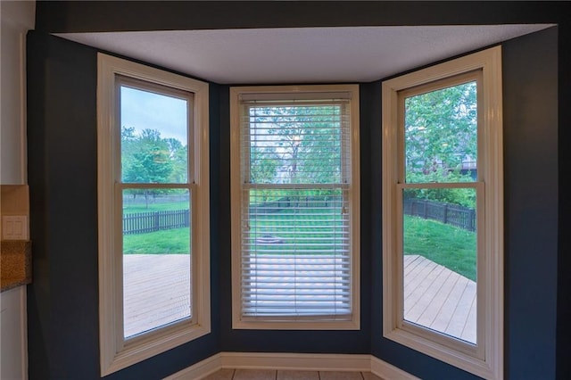 doorway featuring tile patterned flooring, a wealth of natural light, and baseboards
