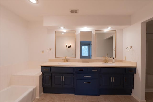 bathroom with visible vents, a garden tub, double vanity, and a sink