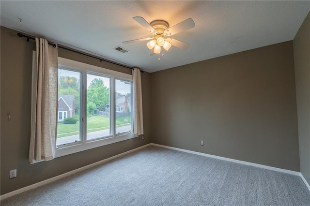 carpeted empty room with visible vents, ceiling fan, and baseboards