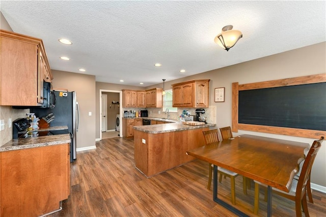 2136 Alder St, Leavenworth, KS 66048 - kitchen with brown cabinets, a textured ceiling, a peninsula, and dark wood-style floors