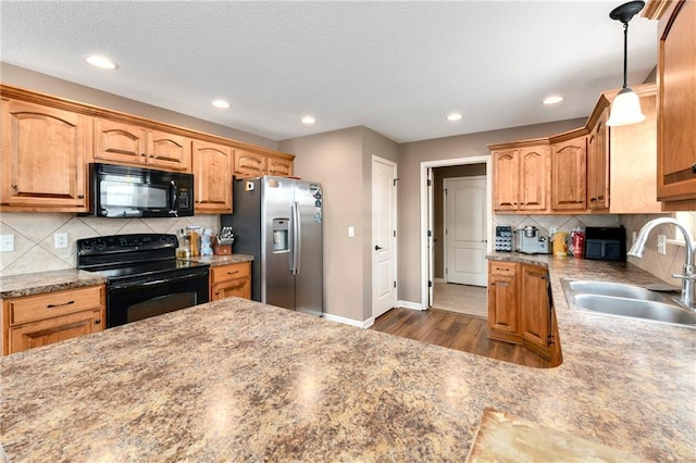 2136 Alder St, Leavenworth, KS 66048 - kitchen featuring decorative backsplash, a sink, dark wood finished floors, black appliances, and hanging light fixtures