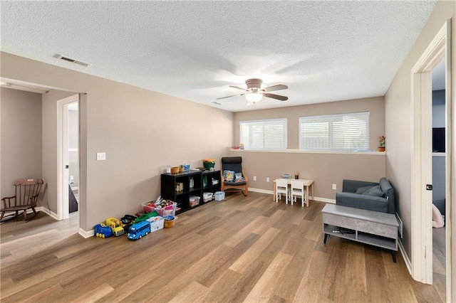 2136 Alder St, Leavenworth, KS 66048 - living area featuring a textured ceiling, a ceiling fan, wood finished floors, and visible vents