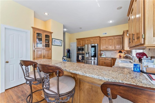 9800 W 147th St, Overland Park, KS 66221 - kitchen featuring stainless steel appliances, a peninsula, light stone countertops, light wood-type flooring, and recessed lighting