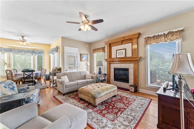9800 W 147th St, Overland Park, KS 66221 - living room featuring a ceiling fan, healthy amount of natural light, a tiled fireplace, and light wood-style floors