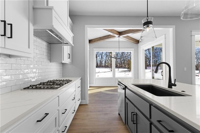 kitchen with tasteful backsplash, white cabinets, custom range hood, a sink, and appliances with stainless steel finishes
