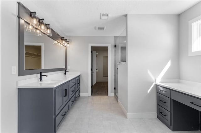 bathroom with a stall shower, double vanity, a sink, and visible vents