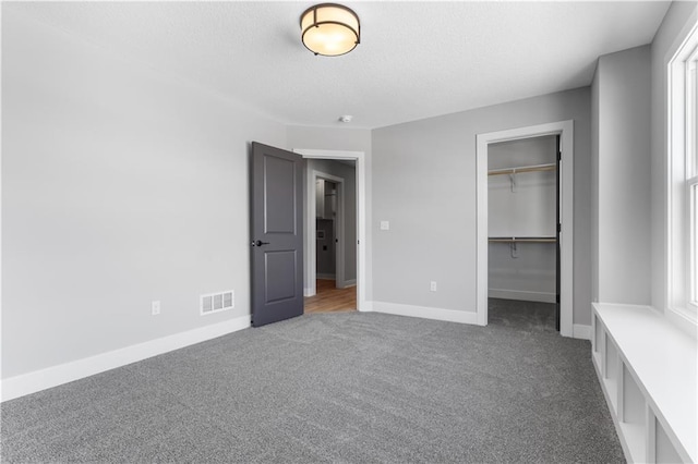 unfurnished bedroom featuring carpet flooring, a textured ceiling, visible vents, and baseboards