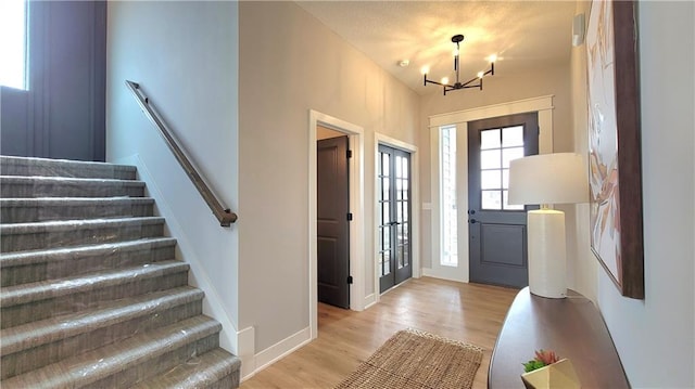 entrance foyer with a chandelier, light wood-type flooring, baseboards, and stairs