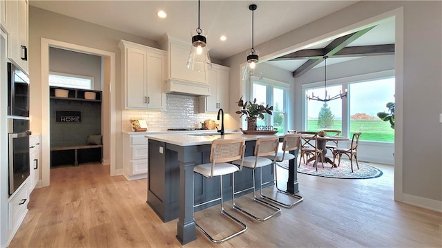 kitchen featuring vaulted ceiling with beams, decorative backsplash, light countertops, a sink, and white cabinetry