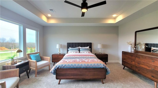 bedroom with carpet flooring, visible vents, baseboards, and a tray ceiling