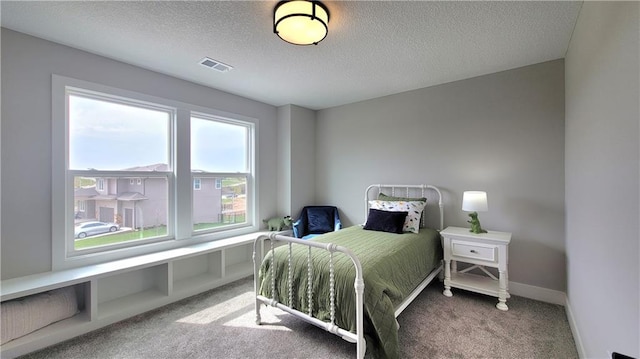 bedroom featuring carpet flooring, a textured ceiling, visible vents, and baseboards