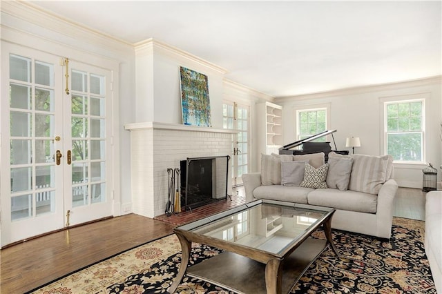 living room with wood finished floors, ornamental molding, a brick fireplace, baseboards, and french doors