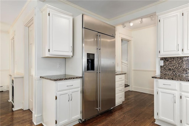 kitchen featuring dark stone counters, white cabinetry, built in fridge, and dark wood-style flooring