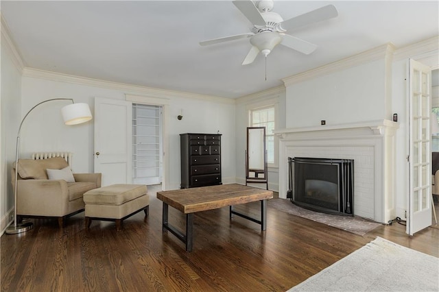 living area with crown molding, ceiling fan, wood finished floors, and a fireplace