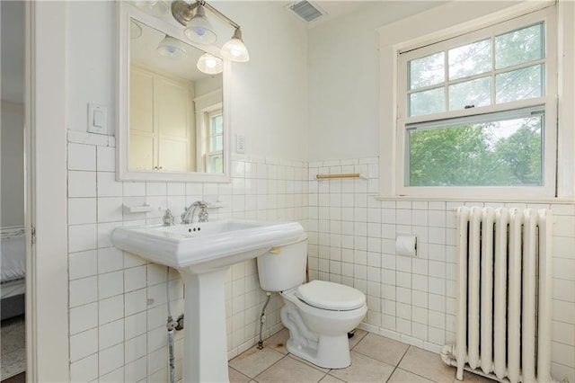 bathroom with tile walls, tile patterned floors, toilet, visible vents, and radiator heating unit