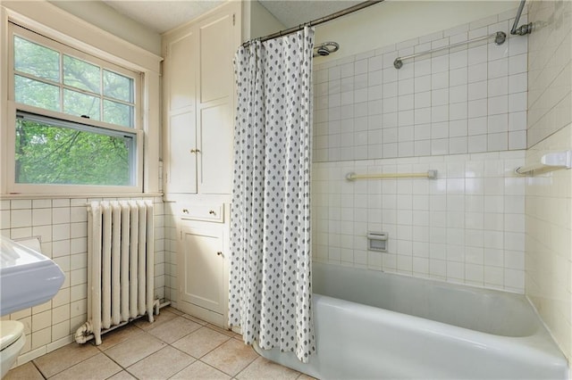 full bathroom featuring tile patterned floors, tile walls, radiator heating unit, shower / bathtub combination with curtain, and toilet