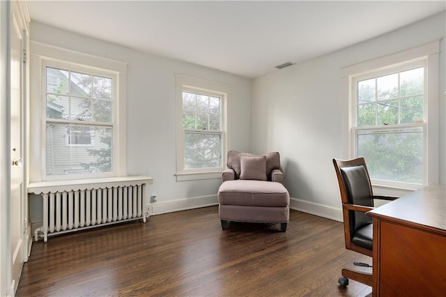 office area with radiator, dark wood-style floors, visible vents, and baseboards