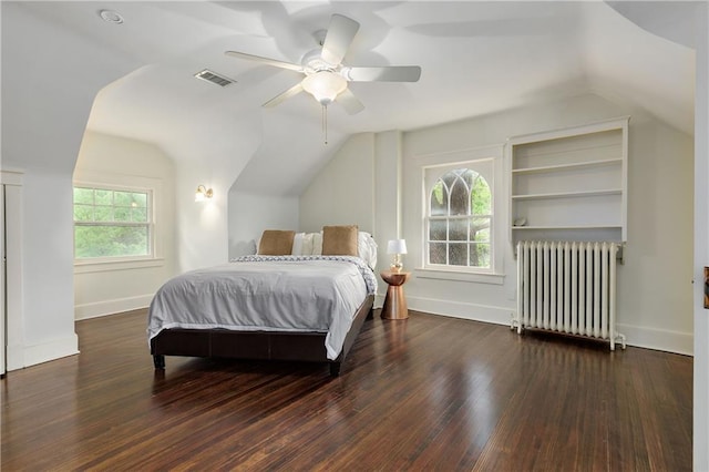 bedroom with wood finished floors, radiator, baseboards, visible vents, and lofted ceiling